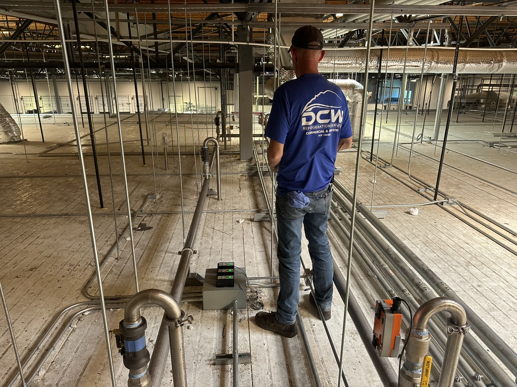 DCW crew member on jobsite during glycol piping installation for rooftop cooler refrigeration